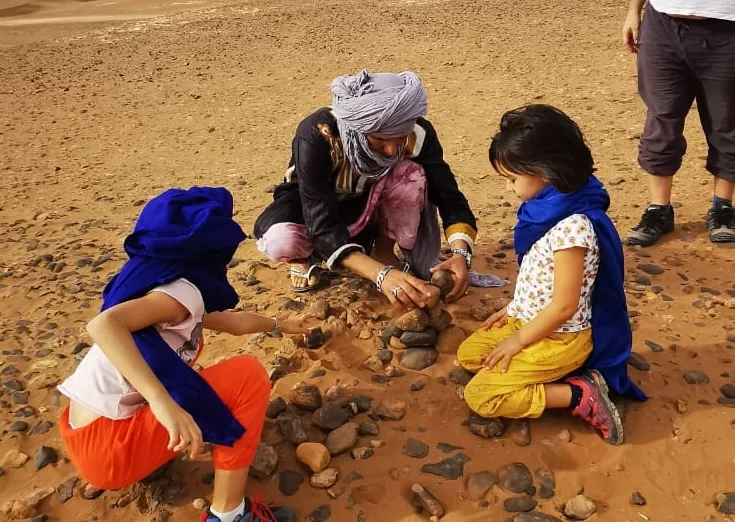 Children on a tour of Morocco plucking out fossils in the desert