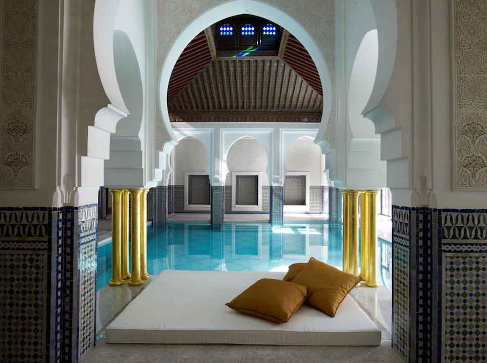Luxurious Moroccan spa with traditional Islamic architecture featuring horseshoe arches, geometric zellige tilework, and a serene indoor pool - perfect destination for vacation packages to Marrakech seeking authentic wellness experiences
