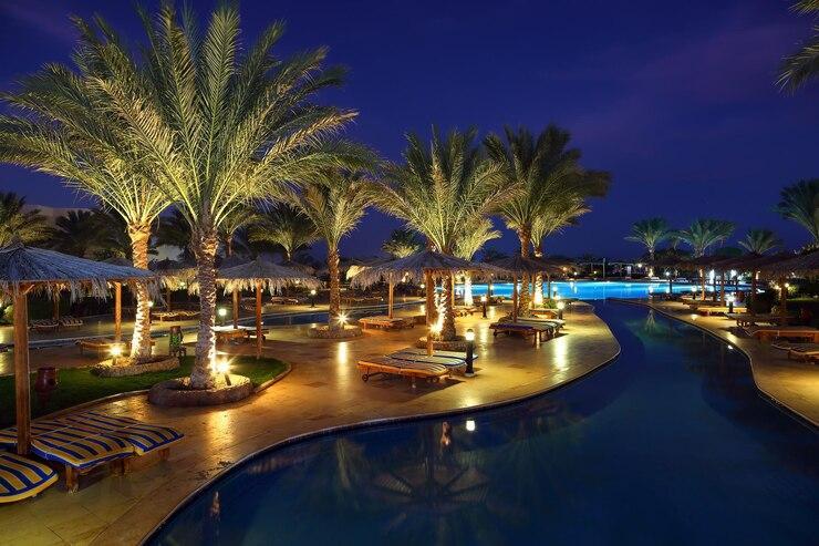 Luxurious Moroccan resort pool area at night with illuminated palm trees and elegant loungers, reflecting the premium hospitality and relaxation experiences delivered by the best Morocco tour companies for discerning travelers
