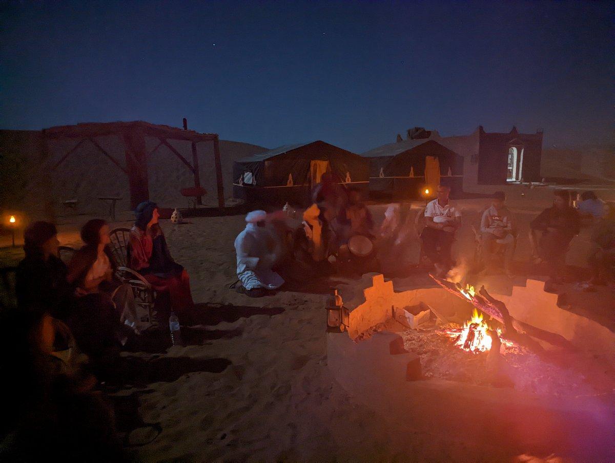 Magical Sahara Desert camping experience with traditional Berber tents and campfire gathering under starlit skies, showcasing the authentic desert adventures included in comprehensive vacation packages to Marrakech