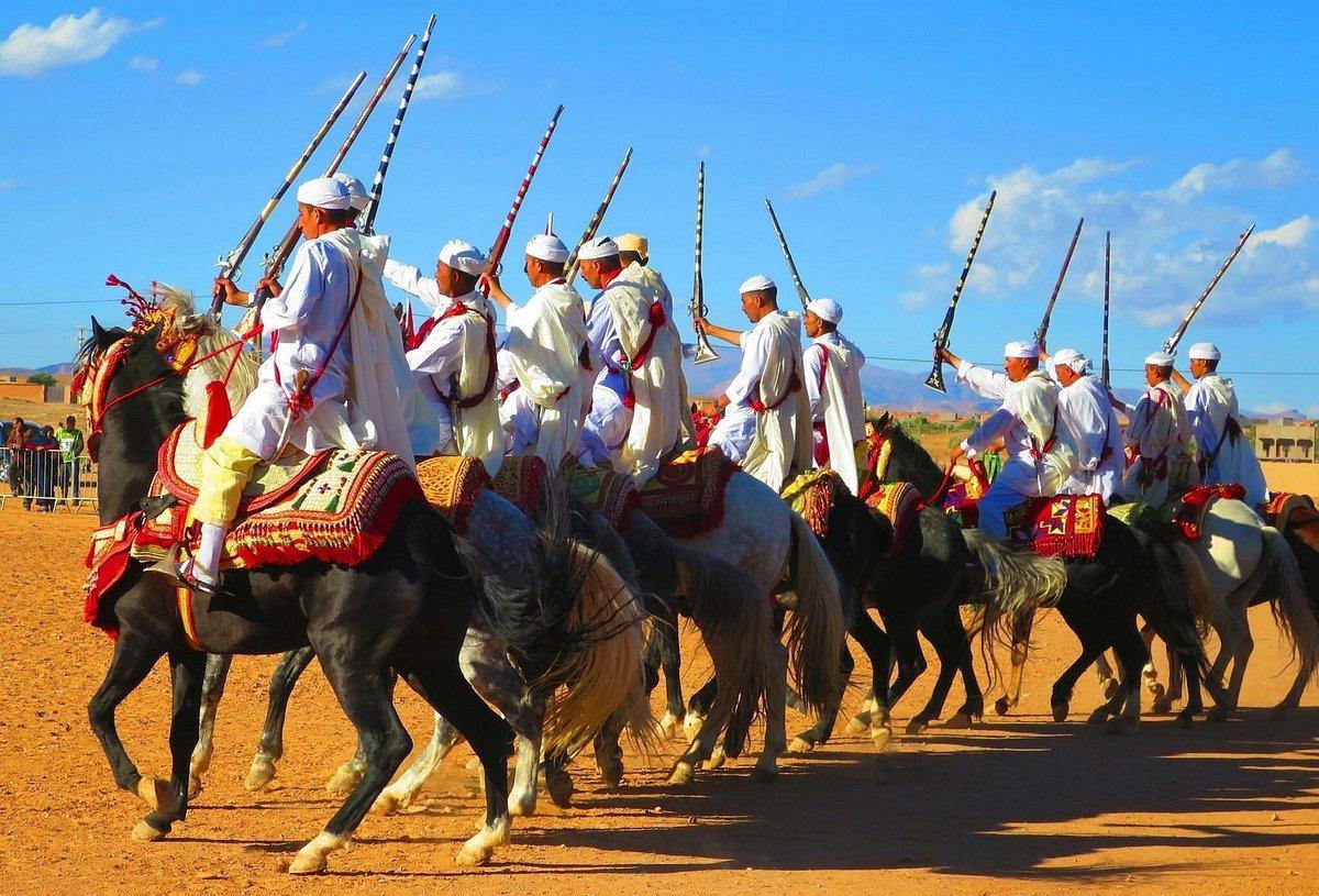 raditional Moroccan horsemen dressed in white performing a cultural fantasia with rifles raised high, showcasing the vibrant heritage and unique experiences offered by the best Morocco tour companies for immersive cultural tours raditional Moroccan horsemen dressed in white performing a cultural fantasia with rifles raised high, showcasing the vibrant heritage and unique experiences offered by the best Morocco tour companies for immersive cultural tours