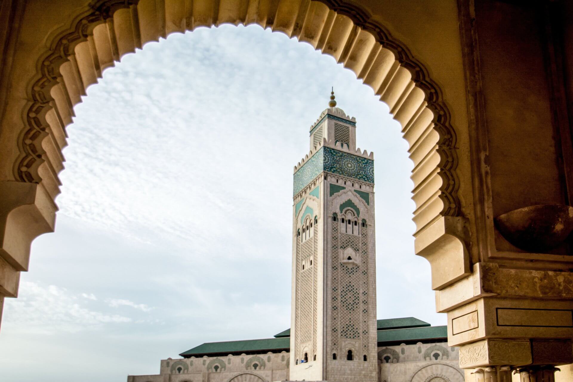 Is Casablanca Safe: A Luxury Operator's Candid Take on Morocco's Largest City 5 The ornate minaret of Hassan II Mosque in Casablanca framed through a carved Moorish arch, best visited in spring or autumnç