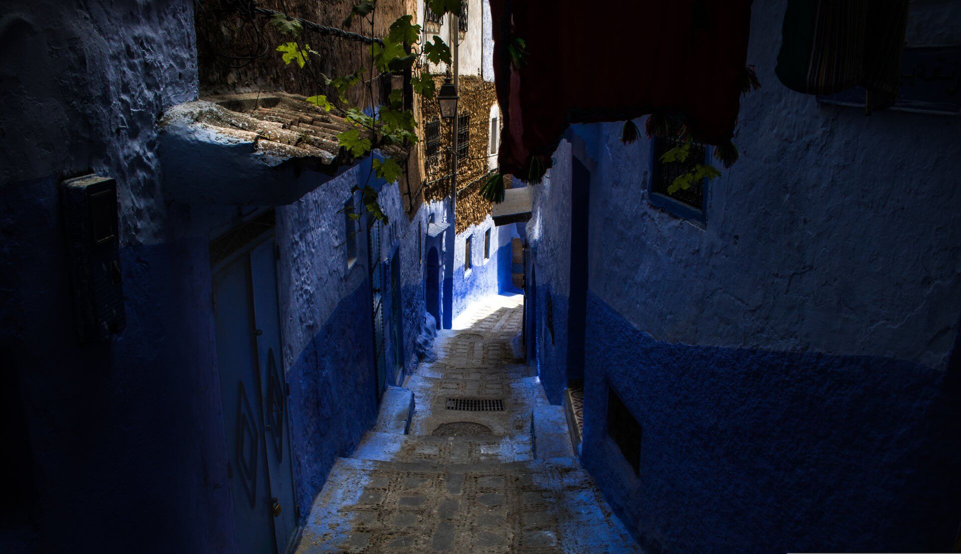 Visit Morocco: A Luxury Journey Through Imperial Cities, Atlas Peaks and Sahara Dunes 8 Narrow cobblestone alley lined with blue-painted walls in Chefchaouen, best explored during the mild spring or autumn months
